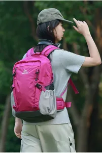 Zaino da trekking leggero rosa e grigio indossato da modella in ambiente boschivo