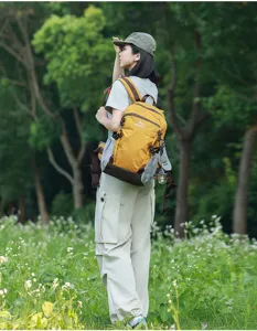 Foto lifestyle all'aperto di una donna con uno zaino da trekking giallo leggero nella natura.