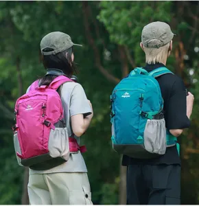 Vista posteriore di due escursionisti con zaini sportivi rosa e verde petrolio all'aperto