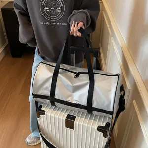 Dettaglio della borsa da viaggio argento fissata sul manico della valigia per viaggiare