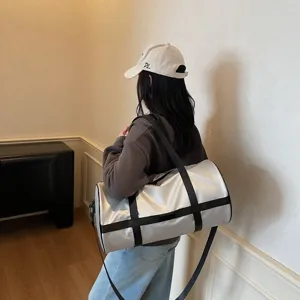 Borsa sportiva cilindrica argento con cinghie nere mostrata sulla spalla della modella.