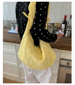 Gedetailleerde weergave van een gele gewatteerde hobo tas met hartborduursel in een café.