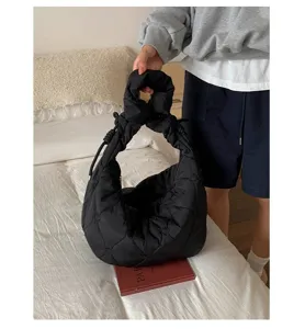 Detailopname van zwarte gewatteerde hobo-tas met hartborduursel en knoopdetail.