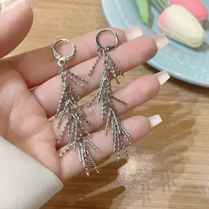 Close-up detail of elegant silver long tassel earrings with a feather-like design.