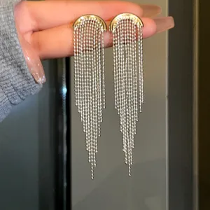 Macro detail of elegant long silver beaded tassel earrings with gold semicircular top