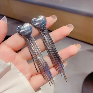 Detailed macro view of silver heart-shaped earrings with elegant long tassel dangles.