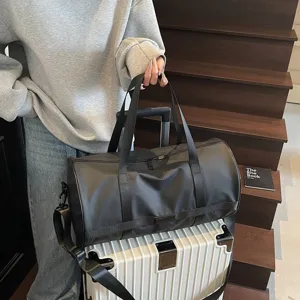 Grande borsa sportiva nera posata su una valigia bianca sulle scale per il viaggio.
