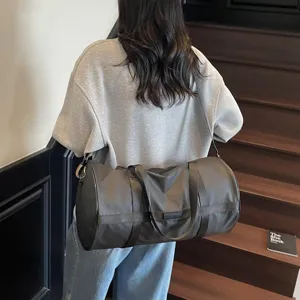Modello che porta una grande borsa sportiva grigio scuro a tracolla su una scala