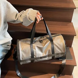 Vista dettagliata di una grande borsa sportiva in nylon kaki tenuta in mano su scale