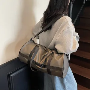 Foto lifestyle di una grande borsa da palestra marrone portata a spalla su scale