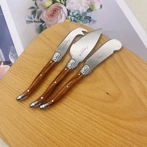Nahaufnahme des 3-teiligen Laguiole-Käsemesser-Sets mit Holzmaserungsgriffen auf Holz.