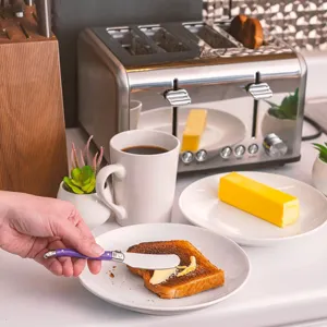 Primer plano de un cuchillo de mantequilla Laguiole morado untando mantequilla en tostadas