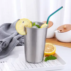 Vaso de acero inoxidable con pajita de colores, rodaja de limon y hielo detalle vista