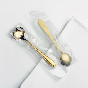 Close-up detail of golden rose and petal spoons in sealed packaging, elegant coffee tableware.