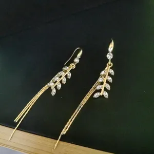Detail of gold wheat ear tassel earrings with shimmering marquise cubic zirconia.