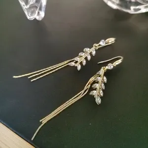 Detailed view of gold-tone wheat ear tassel earrings featuring shimmering clear crystals.