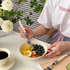 Macro view of cream curved handle spoon being used with a healthy fruit bowl.