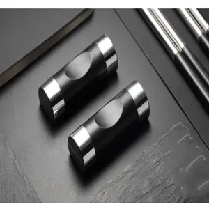 Close-up of modern black and silver alloy chopstick rests on a textured stone surface