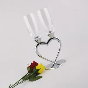 Detail view of crystal glass champagne flutes set with silver heart-shaped holder for weddings.