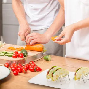 Κοντινό πλάνο ανοξείδωτων βάσεων για taco σε κουζίνα με φρέσκα λαχανικά.