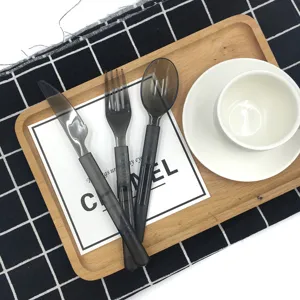 Detailaufnahme eines Einweg-Bestecksets aus grauem Kunststoff, arrangiert auf einem Holztablett