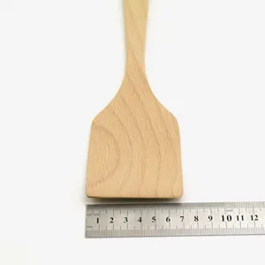 Macro detail of beech wood cooking spatula with steel ruler measuring the head width