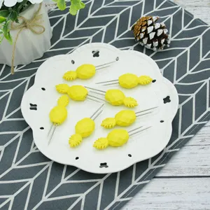 Detailed view of yellow pineapple-shaped corn holders on a white decorative plate