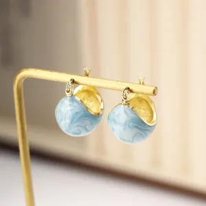 Macro detail of vintage gold hoop earrings with light blue marble enamel glaze finish