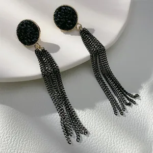 Close-up of vintage black tassel earrings with circular textured studs and long chains