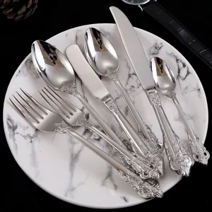 Detailed view of ornate silver-plated vintage royal style cutlery set on marble plate