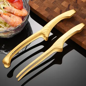 Close-up of gold stainless steel kitchen tongs with non-slip texture on a dark surface.