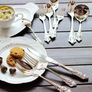 Elegant vintage silver-plated cutlery set with ornate embossed handles on wooden table