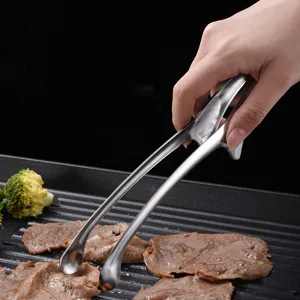 Close-up of stainless steel BBQ tongs flipping meat on a black ribbed grill pan