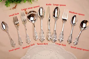 Ornate vintage silver-plated cutlery set including various spoons, forks, and knife