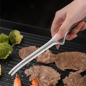 Detailed macro view of stainless steel BBQ tweezers flipping grilled meat on a black grill pan