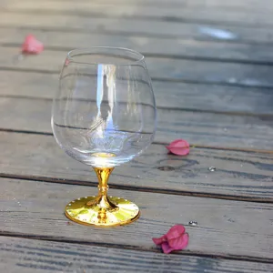 Nahaufnahme eines Kristall-Brandyglases mit goldfarbenem, diamantbesetztem Metallstiel