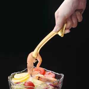 Golden stainless steel food tongs picking up a shrimp from a salad bowl detail