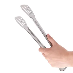 Nahaufnahme einer Hand, die eine Grillzange aus Edelstahl mit Schlitzen hält