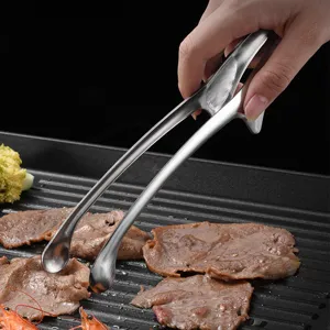 Macro detailed view of stainless steel Korean BBQ tongs flipping meat on a professional grill