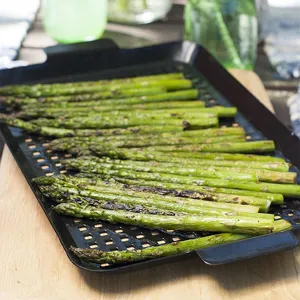 Macro-opname van gegrilde asperges op een zwarte geperforeerde rechthoekige grillpan
