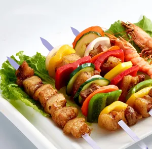 Detailaufnahme von Edelstahl-Grillspießen mit gegrilltem Fleisch, Paprika und Garnelen
