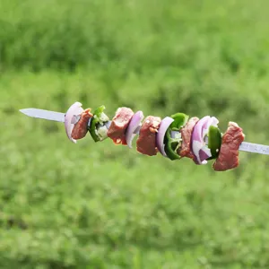 Makro-Detailansicht von rohem Fleisch und Zwiebeln auf einem Grillspieß aus Edelstahl