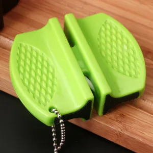 Macro view of a portable green mini knife sharpener showing non-slip grip on wood