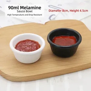 Detail of 90ml black and white melamine sauce bowls for dipping on a wooden board