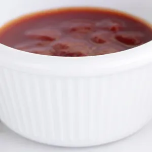 Close-up macro detail showing a white ceramic dipping sauce cup filled with tomato ketchup