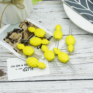 Close-up of eight yellow pineapple-shaped corn holders with stainless steel tines