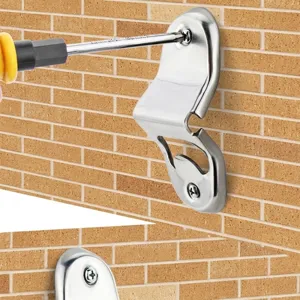 Wall-mounted stainless steel bottle opener being installed on a brick wall with a screwdriver