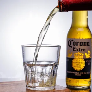 Detailed action shot of refreshing beer pouring into a clear acrylic octagonal drinking glass cup
