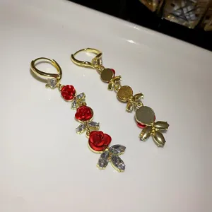 Elegant long drop earrings featuring red rose buds and sparkling crystals in gold setting