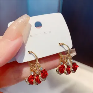 Detailed view of elegant gold hoop earrings featuring red roses and sparkling crystals
